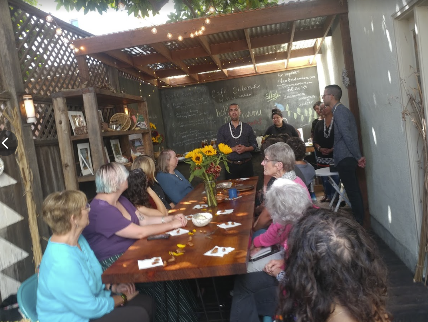 View of diners eating out-of-doors while the business owner gives an educational talk