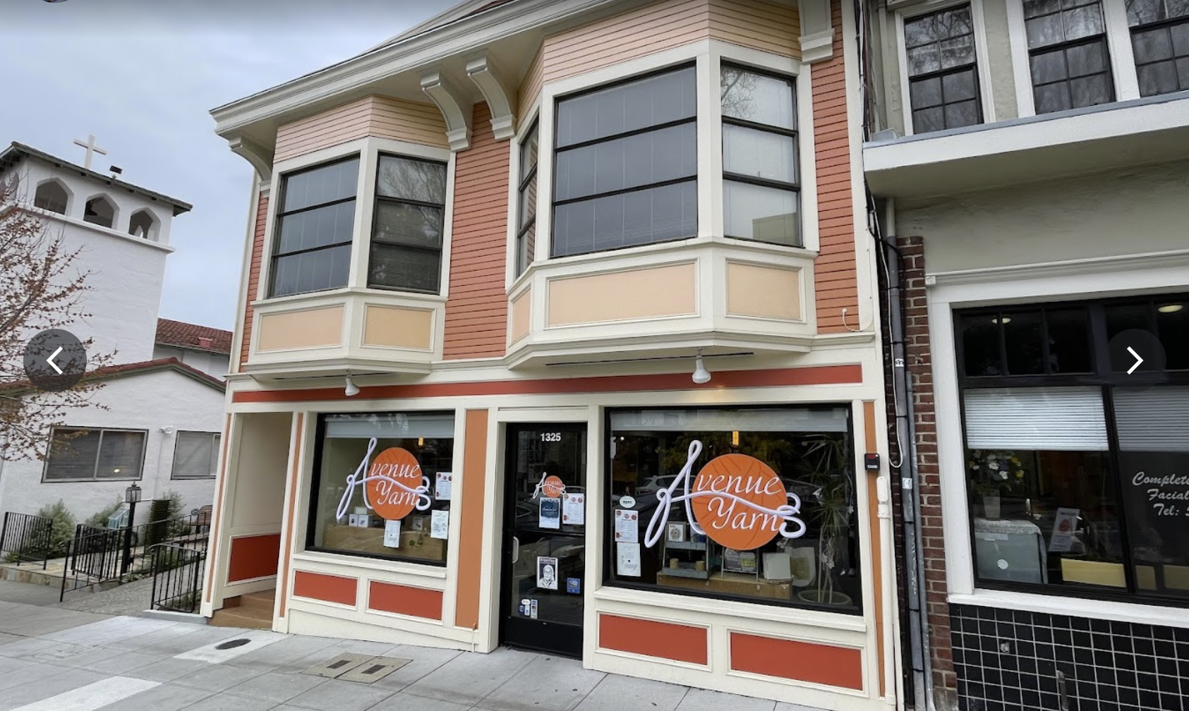 Street-level view of a yarn shop with a large church visible nextdoor to help people realize the location.