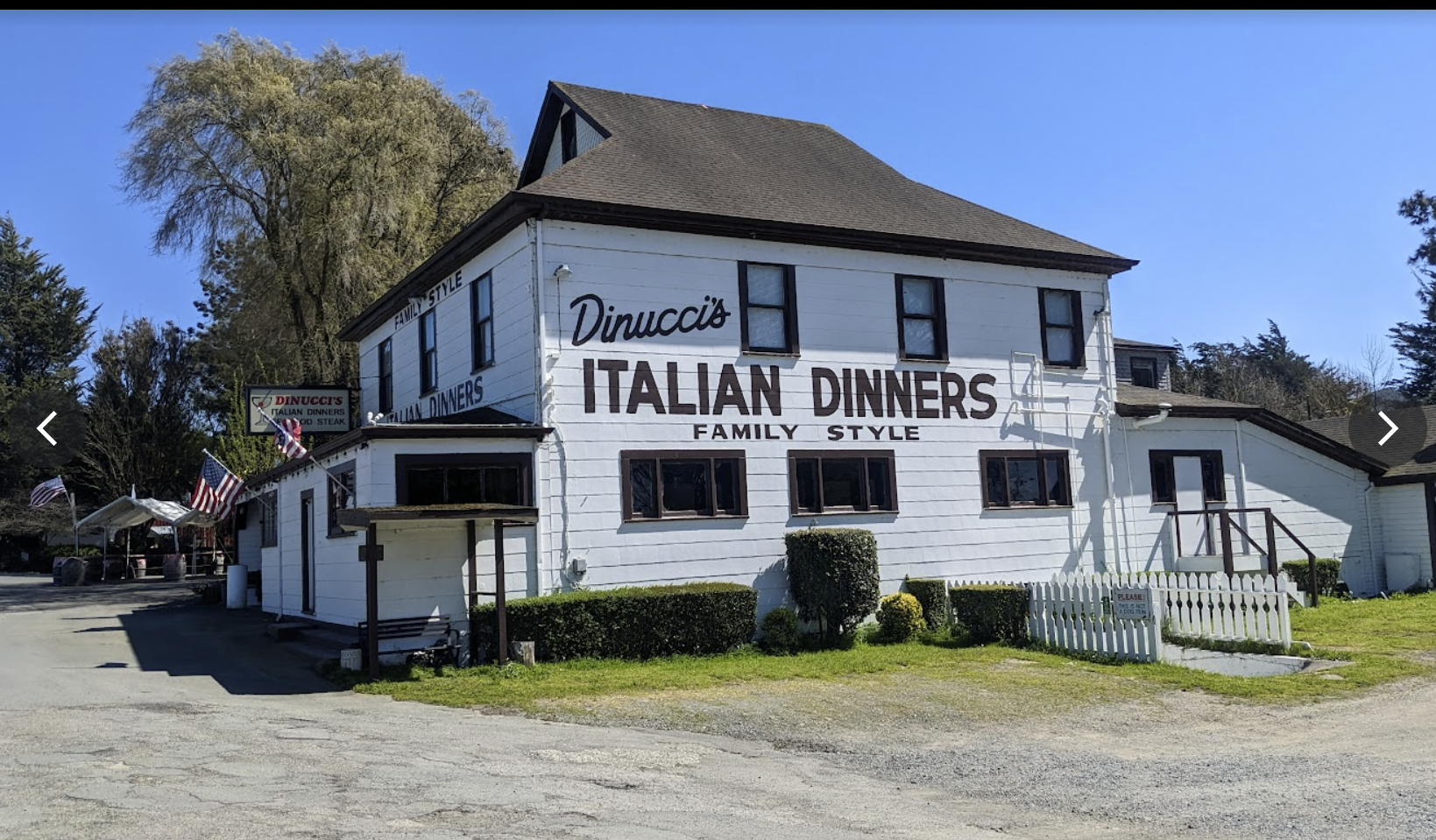 Image of old Italian restaurant with large sign, showing the entirety of the building in good lighting.