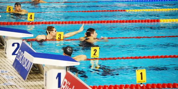 Swimmers wait to see their times in their lanes at a swimming race.