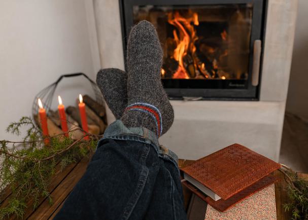 Person wearing socks with their feet up by the fire.