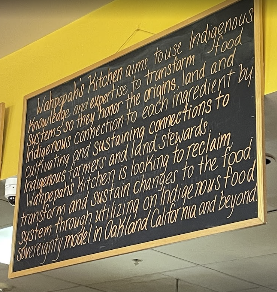A blackboard in a restaurant presents the mission statement of the business regarding Indigenous food.