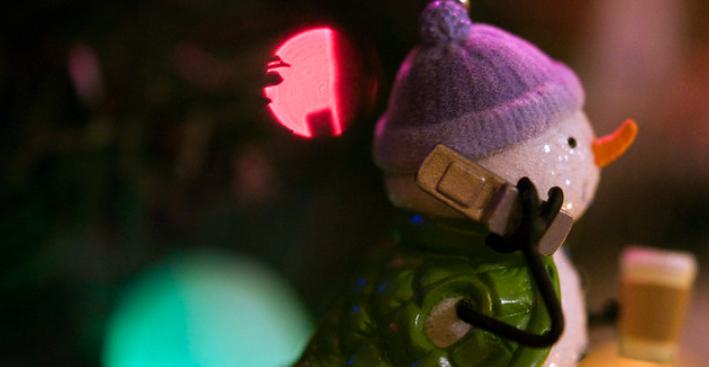 Decorative snowman wearing a purple hat and holding a phone.